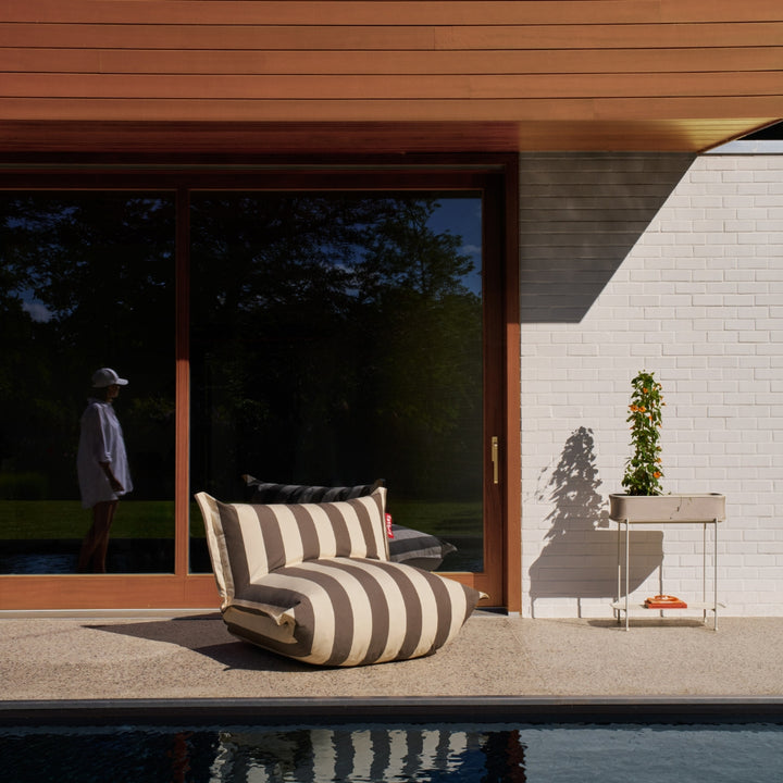 Low-profile outdoor lounge chair with wide backrest, thick cushioning in stripe cacao, by Fatboy, at Desert River Shop.